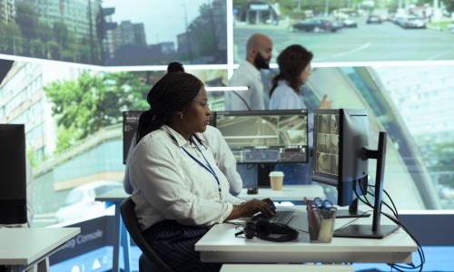 African american government employee monitoring traffic to ensure public safety, reporting any illegal driving by registering the license plate numbers in the database. Using CCTV surveillance.