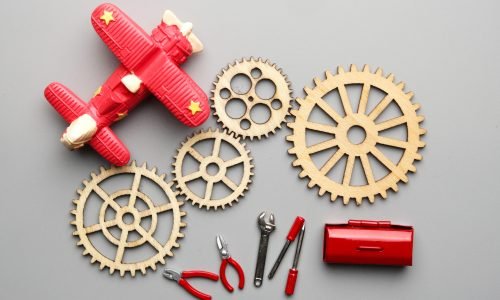 Flatlay picture of wooden gear with aeroplane, repairing tools and toolbox. Technical and mechanical support concept