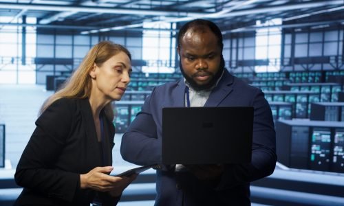 System administrators in data center overseeing server operations using notebook and tablet. Colleagues brainstorming in server hub, ensuring optimal performance and data integrity, camera A