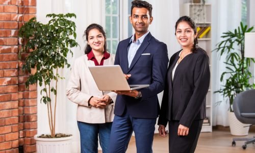 Indian asian business people or business corporate colleagues discussing work on a laptop while standing in posh office